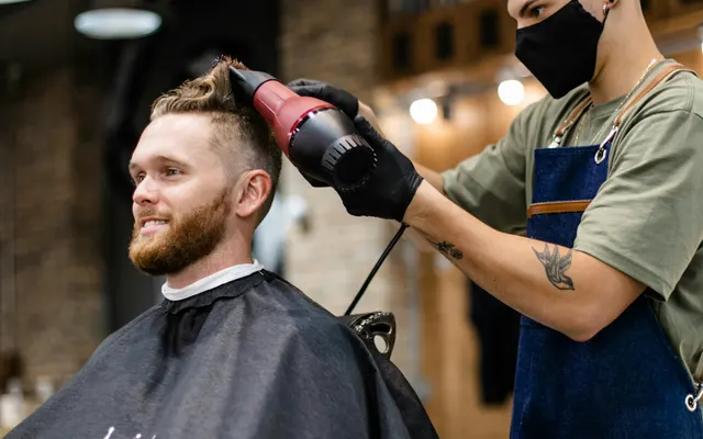 Barbier coiffant un client dans son fauteuil