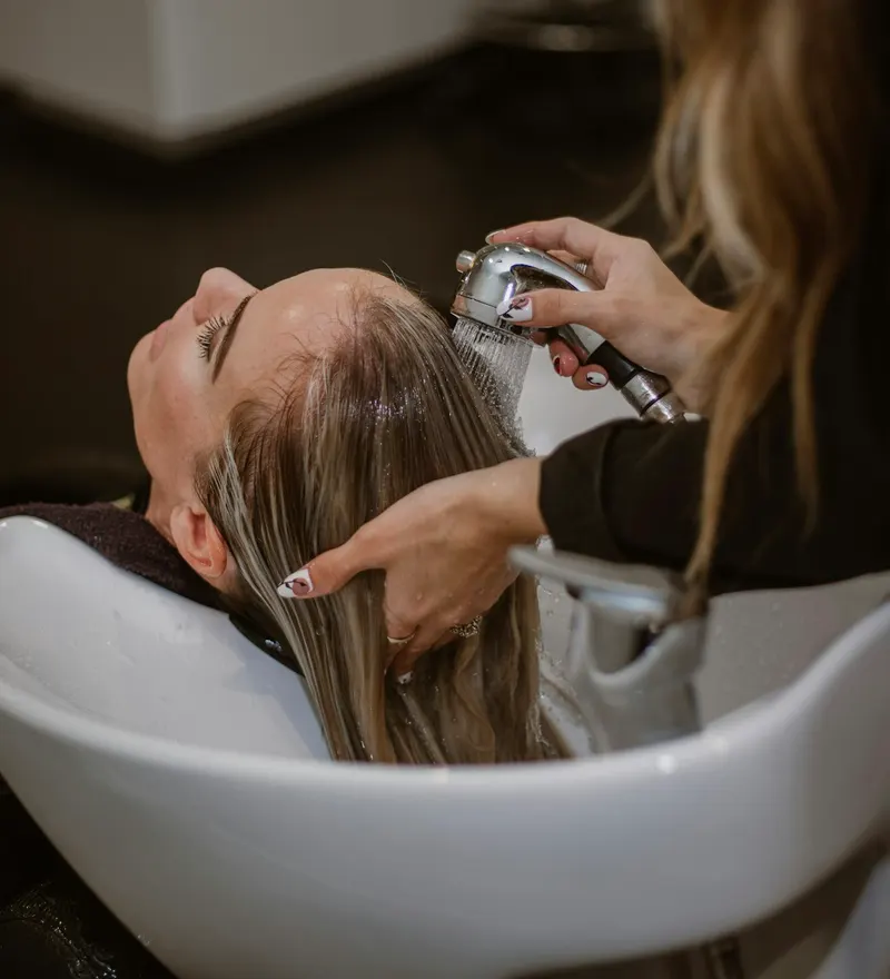 Coiffeuse réalisant une coupe dans son salon