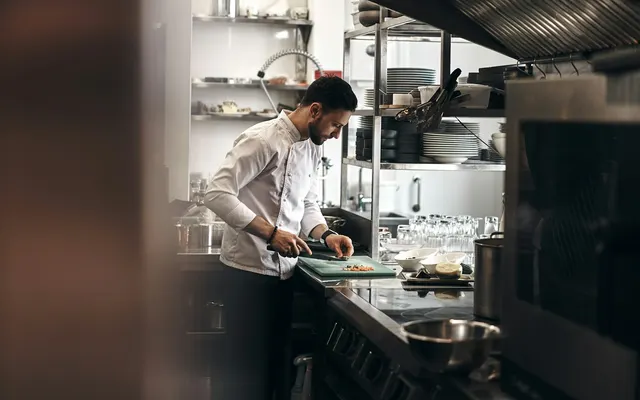 Chef préparant un plat dans la cuisine du restaurant